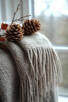Cozy autumn decor with pinecones and a knitted blanket by the window. photo