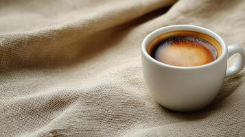 Coffee in a white cup on a textured fabric background during a calm morning. photo