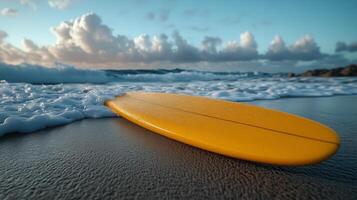 Surfboard resting on the sandy shoreline with waves lapping at its edge during sunset. photo