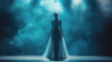 Silhouette of a woman in an elegant gown against a foggy blue backdrop during a stage performance. photo