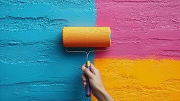 A person paints a textured wall with a colorful roller, applying bright blue, pink, and orange paint. photo