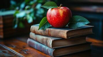 Fresh apple resting on stacked vintage books with greenery in the background. photo