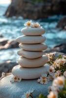 Stacked stones with flowers by the coastline during sunset. photo