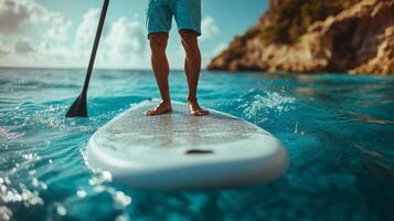 Enjoying stand-up paddleboarding in clear waters near a coastal cliff during sunset. photo