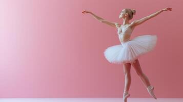 Elegant ballet dancer performing en pointe against a soft pink background in a studio setting. photo