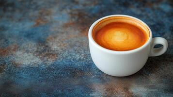 Rich espresso served in a white cup on a textured blue table surface. photo