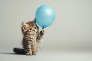 Cute kitten playing with a blue balloon in a playful indoor setting photo