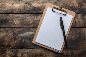 Writing tools on a wooden desk with blank paper and a pen ready for notes or sketches. photo