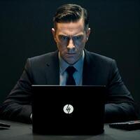 A man in a suit sitting at a desk with a laptop photo