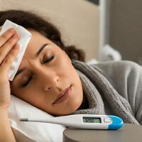 A woman with a fever and a thermometer photo
