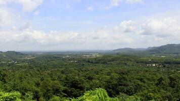 Hilltop panoramic view lush forest, distant village, cloudy sky photo