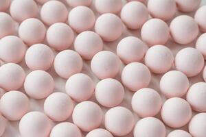 Close-up of pastel pink round candies or sweets arranged in rows. photo
