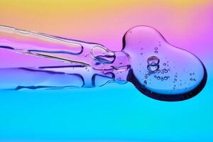 A drop of cosmetic serum and a pipette on a multicolored background in shades of blue and lilac. photo