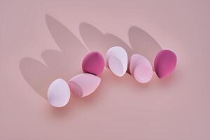 A set of makeup sponges on a pink background. photo