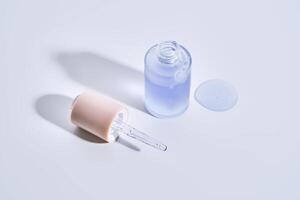 Cosmetic bottle, dropper and a drop of serum on a white background. photo