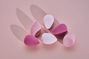 A set of makeup sponges on a pink background. photo