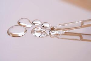 A pipette with a few drops of serum on a beige background. photo