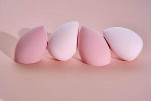 A set of makeup sponges on a pink background. photo