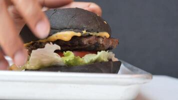 Unique black burger with melted cheese and fresh toppings served video