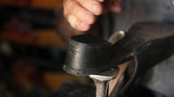 Craftsman repairs a shoe with skillful hands in workshop video