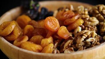 Prunes, dried apricots and nuts in a wooden bowl on a dark background video