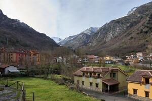 Picturesque town of Pola de Somiedo nestled between towering peaks with snow-covered summits photo