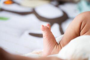 close up of baby foot resting on soft surface, showcasing tiny toes and delicate skin. background features playful design, adding warm and cozy atmosphere photo