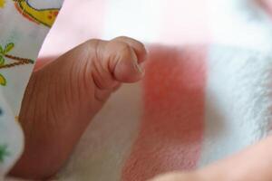 close up of baby hand resting on soft surface, showcasing delicate fingers and skin texture. image evokes sense of tenderness and innocence photo