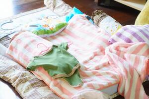 Cozy baby bedding with colorful blankets and clothes on soft surface. scene evokes warmth and comfort, perfect for nursery or play area photo