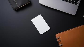 blank business card on sleek black desk with laptop and accessories photo