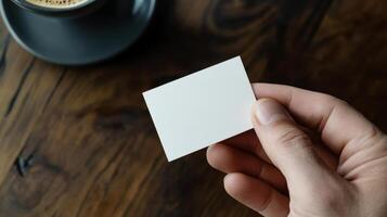 A person holding a white square card with a cup of coffee photo