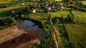 An aerial view of a rural village with a pond photo