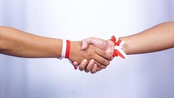Two Hands with Red and White Ribbons are Shaking Hands on White Background photo