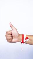 Hands with Red and White Ribbons Showing Thumb Up Sign on White Background photo