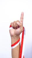 Hand with Red and White Ribbons Showing Number One Sign on White Background photo