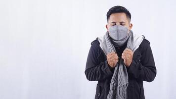 Sick Asian Man Wearing Mask and Scarf with Fever Symptoms on White Background photo