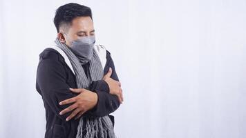 Young Asian Man Wearing Scarf and Jacket Shiver Severely on White Background photo