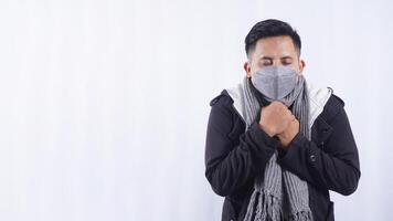 Young Asian Man Wearing Scarf and Jacket Feeling Cold on White Background photo