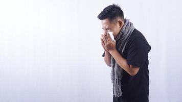 Side View of Unhealthy Asian Man Blows His Nose with Tissue Paper Suffering from Flu on White Background photo