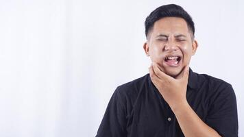 Upset Young Asian Man with Swollen Cheek Suffering from Toothache on White Background photo