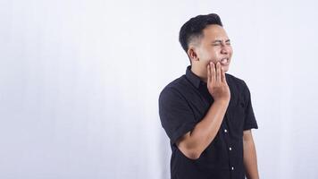 Unhealthy Young Asian Man Touching His Cheek Suffering from Bad Toothache on White Background photo