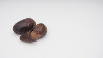 Dried Nutmeg Spice with Broken Skin on White Background photo