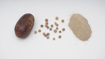 Nutmeg with White Peppercorn Raw and Powder on White Background photo