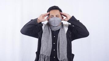 Asian Man Wearing Jacket, Scarf, and Mask Feels Headache on White Background photo