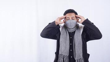 Asian Man Wearing Jacket, Scarf, and Mask Suffering from Bad Headache on White Background photo