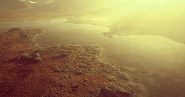 Serene view of a misty lake surrounded by rocky terrain at dawn video