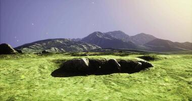 Expansive green terrain with large boulders scattered across the ground video