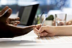 Person signing contract after qualifications aligned with company expectations. Close up of applicant writing signature on forms after making recruiter happy with previous work resume photo