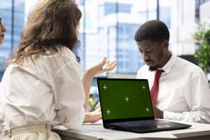 Job interview candidate interested in career advancement, talking with HR employee using isolated screen laptop. Man talking with recruiter checking his CV on mockup notebook to get hired photo