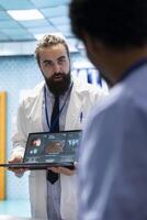 Neurology specialist examines magnetic resonance imaging brain scan with his team in a meeting, looking at tomography for accurate neuroscience diagnosis. Diverse team of neurologist doctors. photo